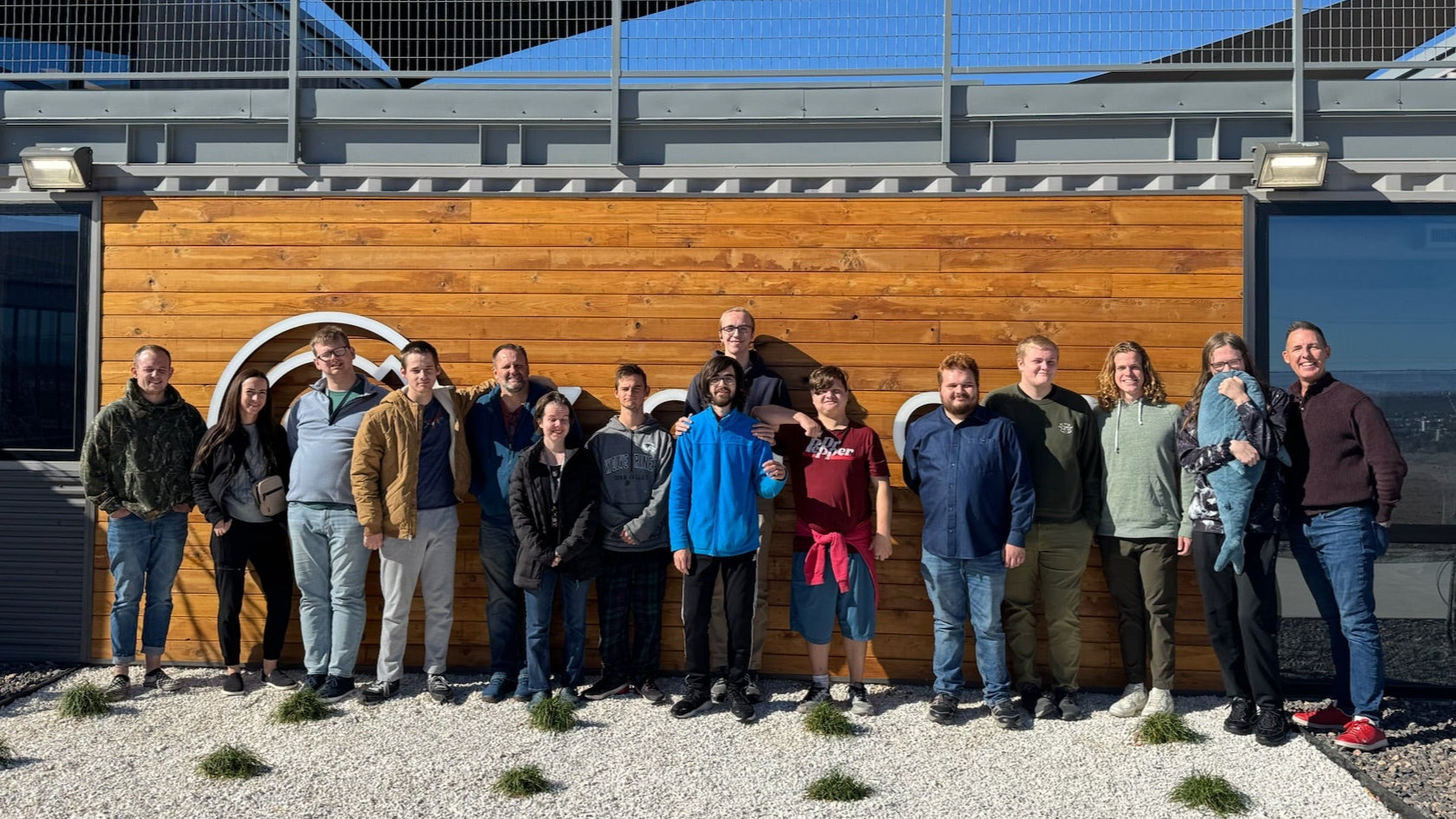 dinkers team posing for a photo in front of a wooden building with a blue sky.
