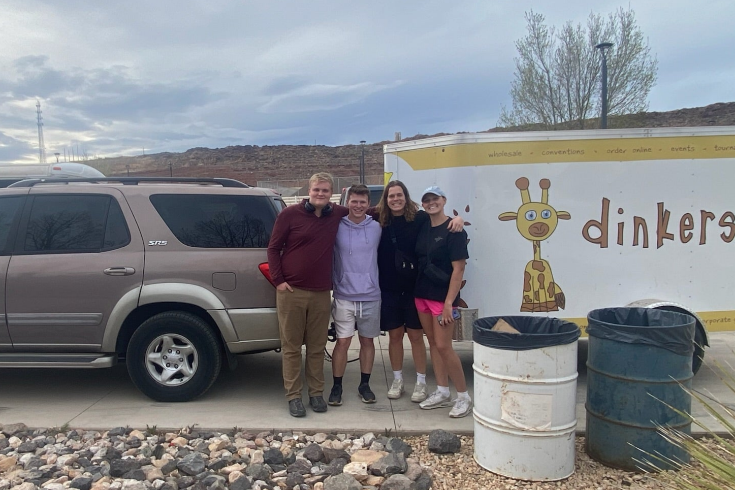 people standing next to SUV pulling a work trailer with "dinkers" and dinkers the giraffe graphics